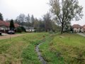 Koryto Polominy v Tasově, pohled směrem po proudu na lávku na horním konci obce